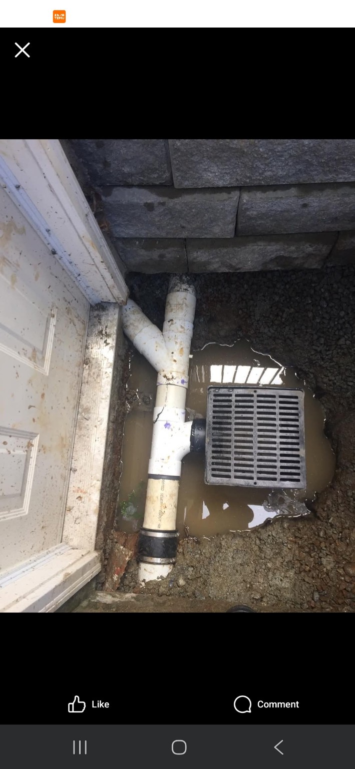 Catch basin and white PVC drainage connections beside a building