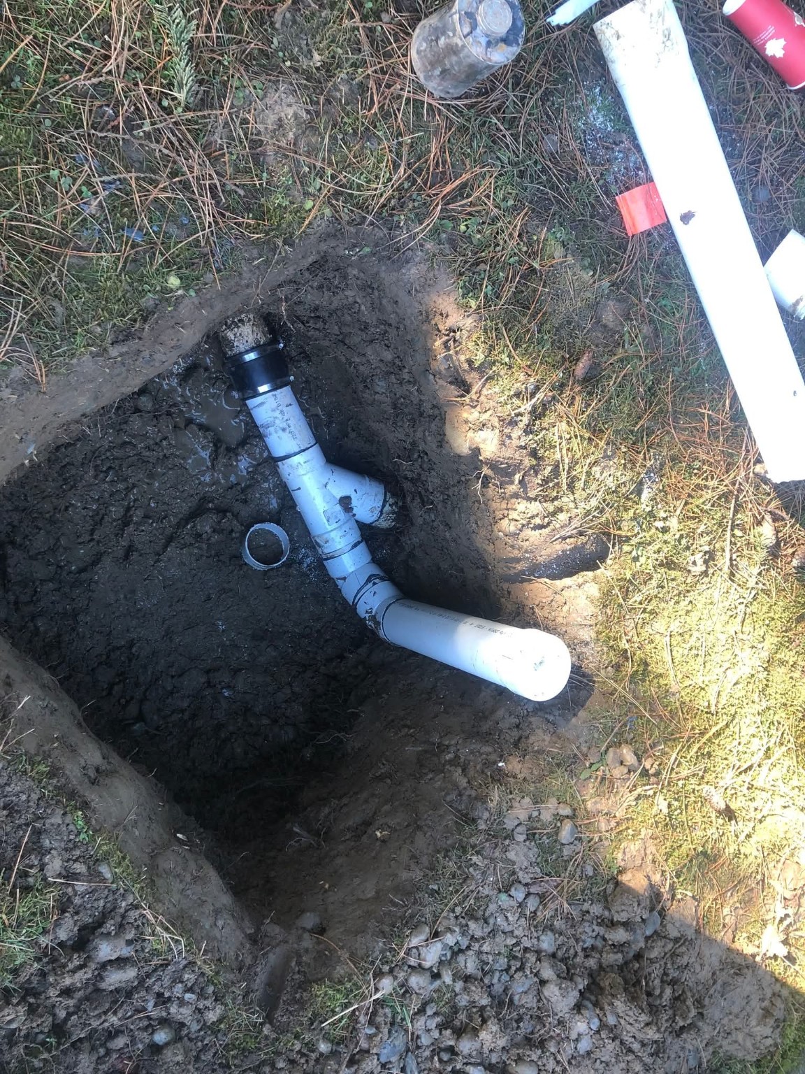 White PVC drainage fittings and pipe connections during perimeter drain repair